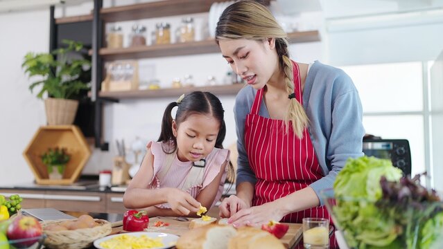 Young Asian Mother Teaching Little Daughter Making Sandwiches In Kitchen Room At Home. Mother And Daughter Helping Together Making Sandwiches For Breakfast. Happy Family, Single Mom Concept