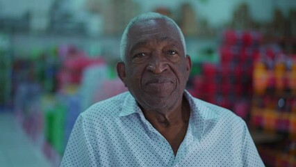 Portrait of an elderly black Brazilian man close-up face looking at camera with neutral expression with grocery products in blurred background