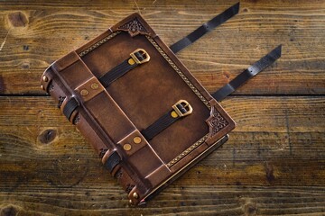Aged leather book cover, design with closure belts - captured on wooden table