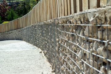 Fence made of mesh and stone with wooden planks