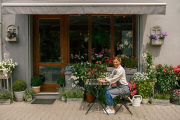 Beautiful flower shop owner wearing apron working on laptop in her store