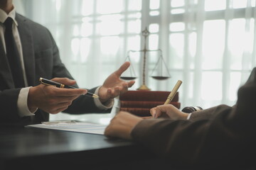 Business and lawyers discussing contract papers with brass scale on desk in office. Law, legal services, advice, justice and law concept picture with film grain effect