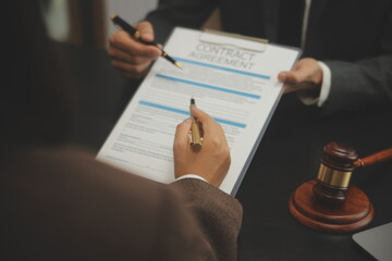 Business and lawyers discussing contract papers with brass scale on desk in office. Law, legal services, advice, justice and law concept picture with film grain effect