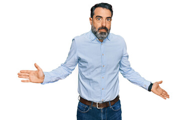 Middle aged man with beard wearing business shirt clueless and confused expression with arms and hands raised. doubt concept.