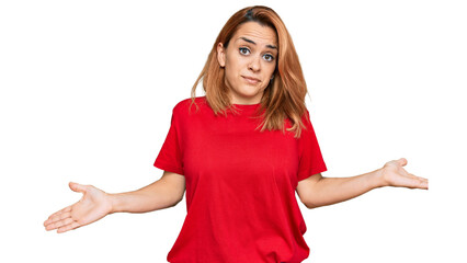 Hispanic young woman wearing casual red t shirt clueless and confused expression with arms and hands raised. doubt concept.