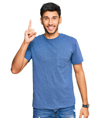 Young handsome man wearing casual clothes pointing finger up with successful idea. exited and happy. number one.