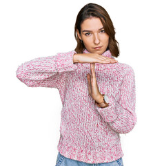 Young caucasian girl wearing wool winter sweater doing time out gesture with hands, frustrated and...