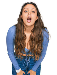 Young hispanic girl wearing casual clothes afraid and shocked with surprise and amazed expression,...