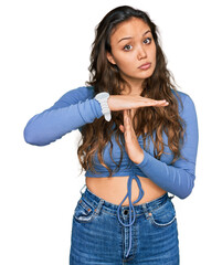 Young hispanic girl wearing casual clothes doing time out gesture with hands, frustrated and...