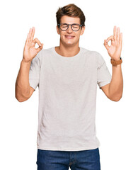 Handsome caucasian man wearing casual clothes and glasses relaxed and smiling with eyes closed doing meditation gesture with fingers. yoga concept.