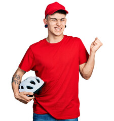 Young caucasian boy with ears dilation wearing delivery uniform and cap holding bike helmet...