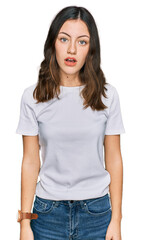 Fototapeta premium Young beautiful woman wearing casual white t shirt in shock face, looking skeptical and sarcastic, surprised with open mouth