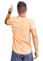 Young handsome man wearing casual clothes posing backwards pointing ahead with finger hand