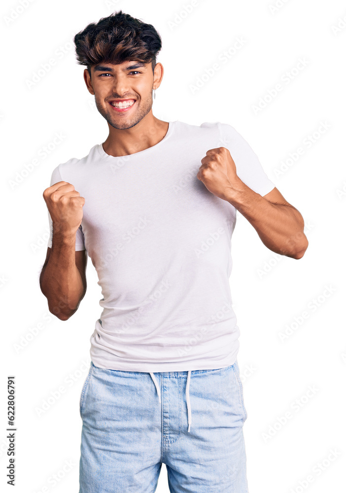 Wall mural Young hispanic man wearing casual clothes excited for success with arms raised and eyes closed celebrating victory smiling. winner concept.