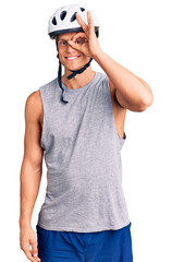 Young handsome man wearing bike helmet doing ok gesture with hand smiling, eye looking through fingers with happy face.