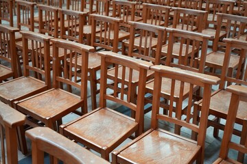 Rows of Wooden Brown Chairs on a stone floor. 