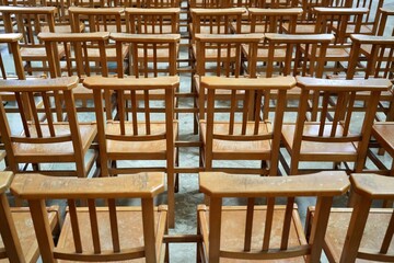 Rows of Wooden Brown Chairs on a stone floor. 