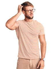 Fototapeta premium Young caucasian man wearing casual clothes and glasses confuse and wondering about question. uncertain with doubt, thinking with hand on head. pensive concept.
