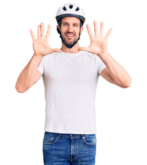 Young handsome man wearing bike helmet showing and pointing up with fingers number ten while smiling confident and happy.