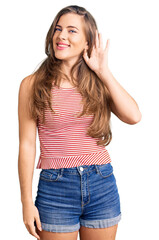 Fototapeta premium Beautiful caucasian young woman wearing casual clothes smiling with hand over ear listening an hearing to rumor or gossip. deafness concept.