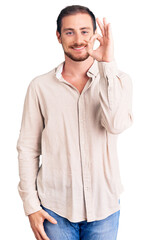 Young handsome caucasian man wearing casual clothes smiling positive doing ok sign with hand and fingers. successful expression.