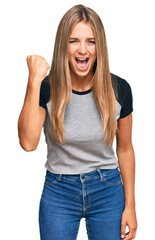 Fototapeta premium Young blonde woman wearing casual clothes angry and mad raising fist frustrated and furious while shouting with anger. rage and aggressive concept.