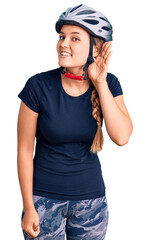 Beautiful caucasian woman wearing bike helmet smiling with hand over ear listening an hearing to rumor or gossip. deafness concept.