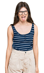 Fototapeta premium Young beautiful caucasian girl wearing casual clothes and glasses sticking tongue out happy with funny expression. emotion concept.