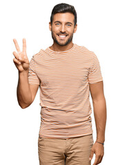 Fototapeta premium Handsome hispanic man wearing casual clothes showing and pointing up with fingers number two while smiling confident and happy.