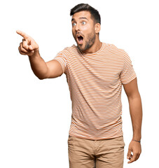 Handsome hispanic man wearing casual clothes pointing with finger surprised ahead, open mouth...