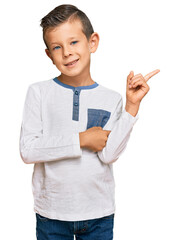 Adorable caucasian kid wearing casual clothes with a big smile on face, pointing with hand and finger to the side looking at the camera.