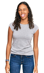 Young african american girl wearing casual clothes sticking tongue out happy with funny expression. emotion concept.