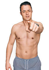 Fototapeta premium Handsome young man wearing swimwear shirtless pointing displeased and frustrated to the camera, angry and furious with you