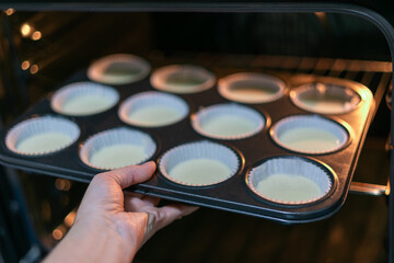 Closeup female hand holding iron mold with group homemade dough for pumpkin muffins. 