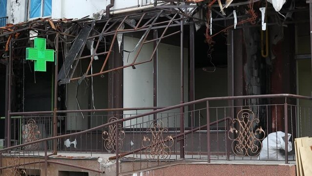 The store burned down after a fire. Remains of an outdoor dining area and restaurant facade after the arson attack. Damaged facade of a retail store and pharmacy on the basement floor of the building.
