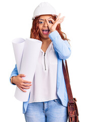 Young latin woman wearing architect hardhat and leather bag holding blueprints smiling happy doing ok sign with hand on eye looking through fingers