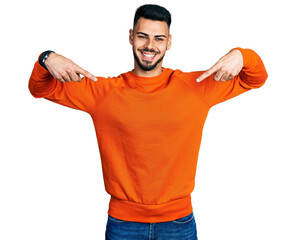 Young hispanic man with beard wearing casual orange sweater looking confident with smile on face,...