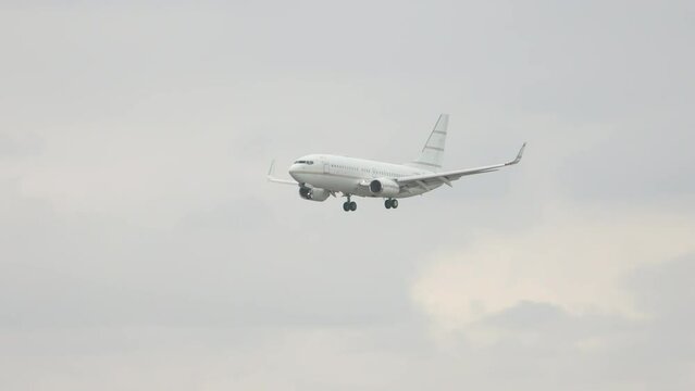 Generic White 737 Type Airliner with No Markings Flying in a Grey Cloudy Sky during Approach into an Airport