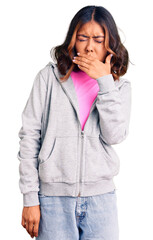 Young beautiful mixed race woman wearing casual sporty clothes feeling unwell and coughing as...