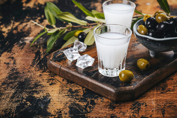 Traditional greek vodka ouzo and marinated olives on rustic wooden table