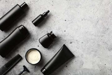 Black cosmetic bottles set on stone table. Men's beauty products concept.