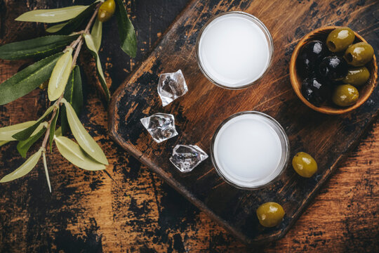 Traditional greek vodka ouzo and marinated olives on rustic wooden table