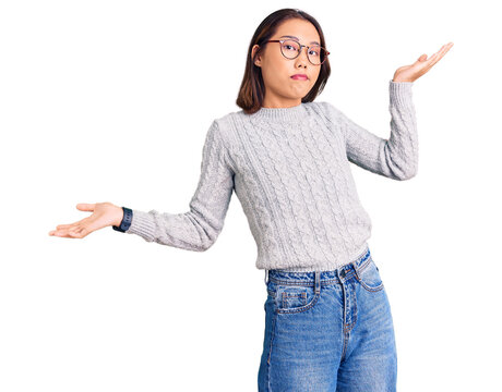 Young beautiful chinese girl wearing casual clothes clueless and confused expression with arms and hands raised. doubt concept.