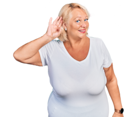 Middle age blonde woman wearing casual white t shirt smiling with hand over ear listening an hearing to rumor or gossip. deafness concept.