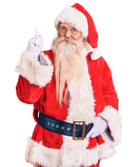 Old senior man with grey hair and long beard wearing traditional santa claus costume pointing finger up with successful idea. exited and happy. number one.