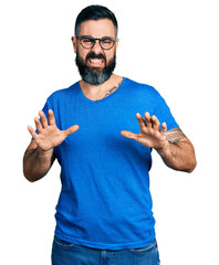 Hispanic man with beard wearing casual t shirt and glasses disgusted expression, displeased and...
