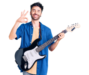 Young hispanic man playing electric guitar doing ok sign with fingers, smiling friendly gesturing excellent symbol