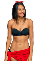 Fototapeta premium Young african american woman wearing bikini looking away to side with smile on face, natural expression. laughing confident.