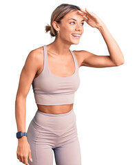 Fototapeta na wymiar Beautiful caucasian woman wearing sportswear very happy and smiling looking far away with hand over head. searching concept.
