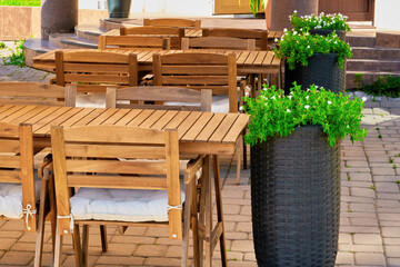 Fototapeta na wymiar wooden furniture, tables and chairs of a cozy outdoor cafe on a clear sunny summer day. beautiful postcard for the designer. desktop background